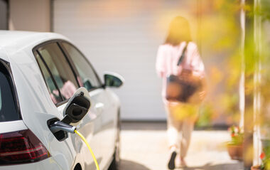 Nahaufnahme eines Ladegeräts für Elektroautos mit einer Frau im Hintergrund