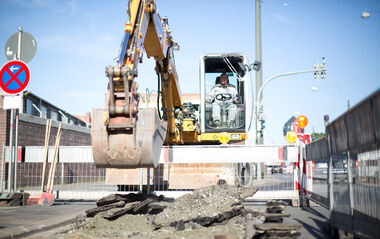 e-netz-Mitarbeiter erledigt Erdarbeiten mit einem Bagger auf einer Baustelle