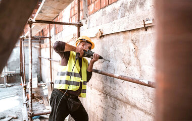 Bauarbeiter bohrt mit einer Bohrmaschine ein Loch in eine Betonmauer